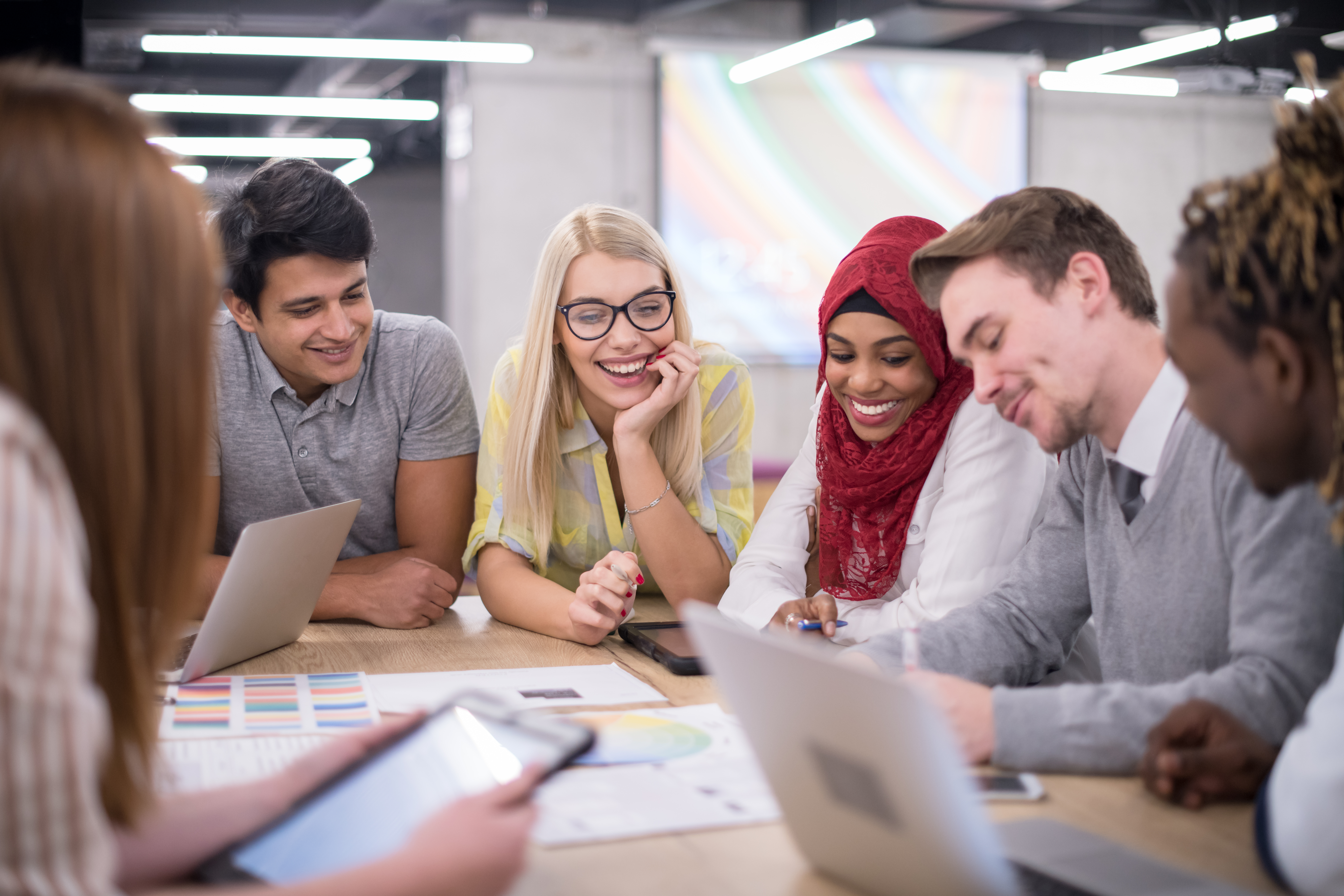 Multiethnic startup business team on meeting in modern bright office interior brainstorming, working on laptop and tablet computer